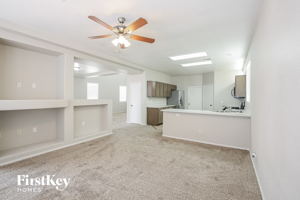an empty living room and kitchen with a ceiling fan