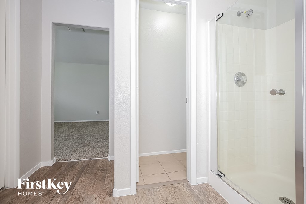 a white shower in a white bathroom with a wooden floor