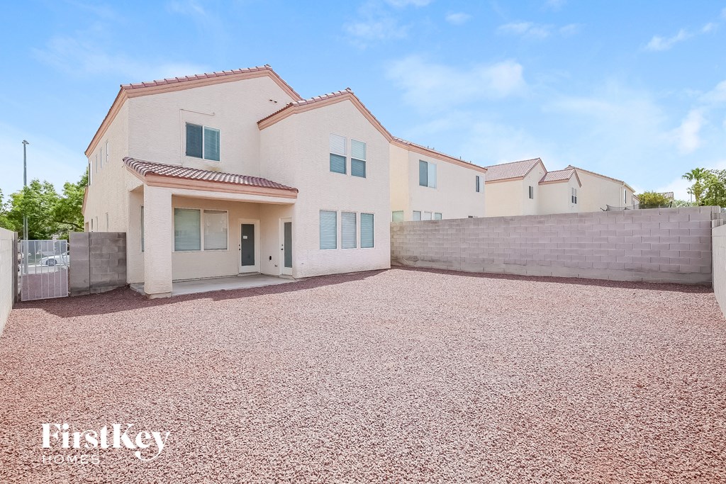 a home with a gravel driveway and a white house