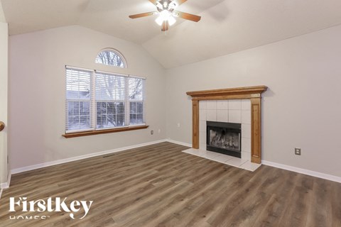 A spacious room with a fireplace and a ceiling fan.