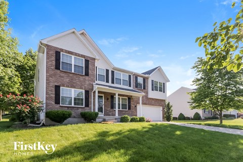 a brick house with white shutters and a lawn