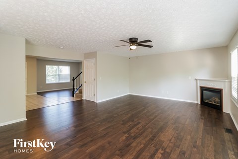 an empty living room with a fireplace and a ceiling fan