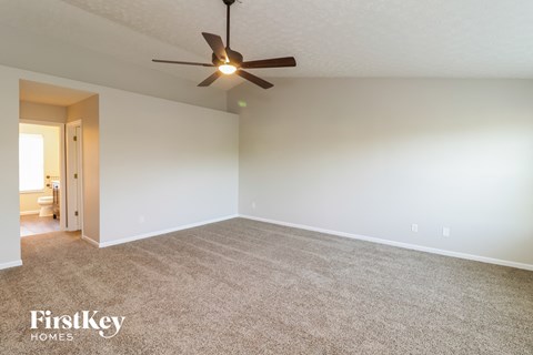the spacious living room with carpet and ceiling fan