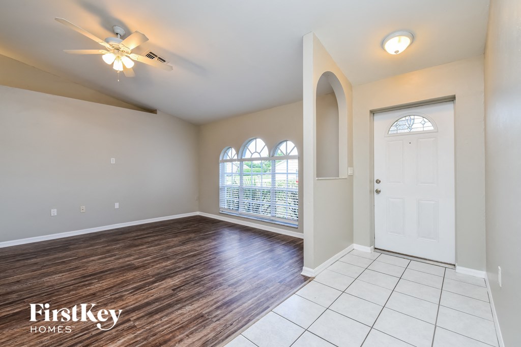 an empty living room with a white door and a window