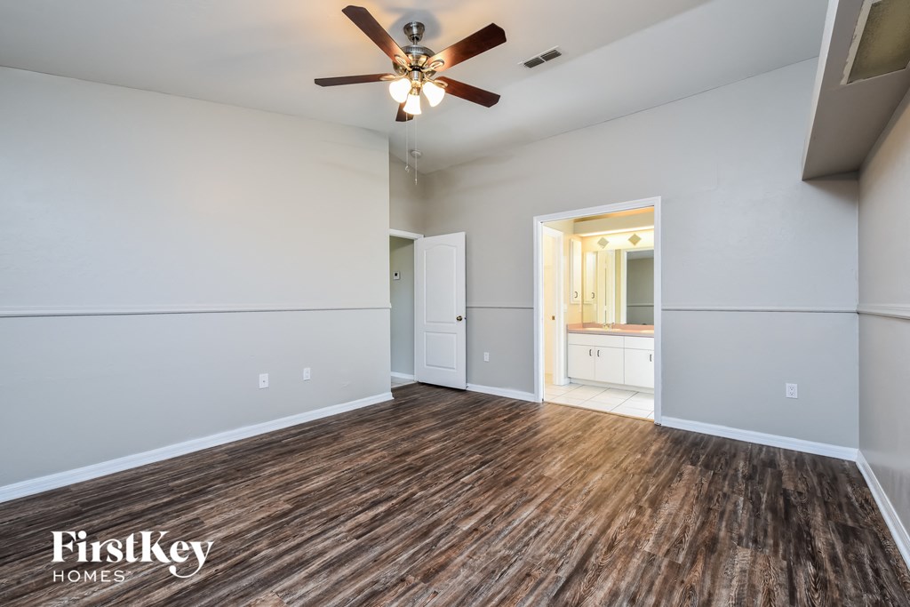 an empty living room with wood flooring and a ceiling fan