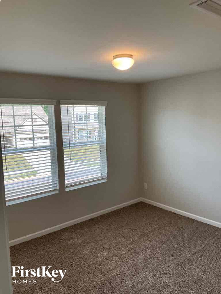 an empty bedroom with two windows and a carpeted floor