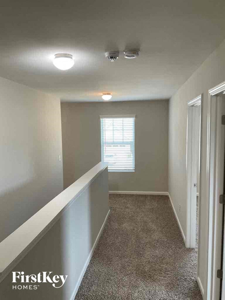 an empty hallway with a window and a carpeted floor