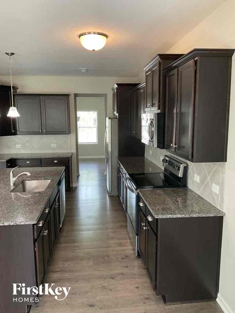 an empty kitchen with black cabinets and stainless steel appliances