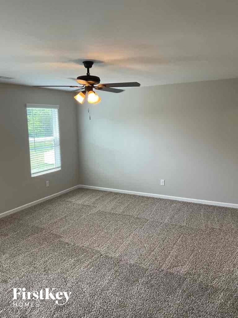 a empty carpeted room with a ceiling fan