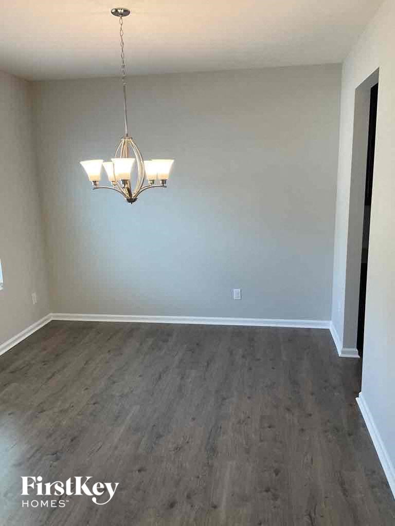 a empty living room with wood floors and a chandelier