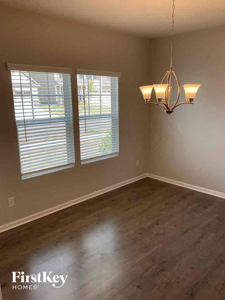 an empty dining room with two windows and a chandelier