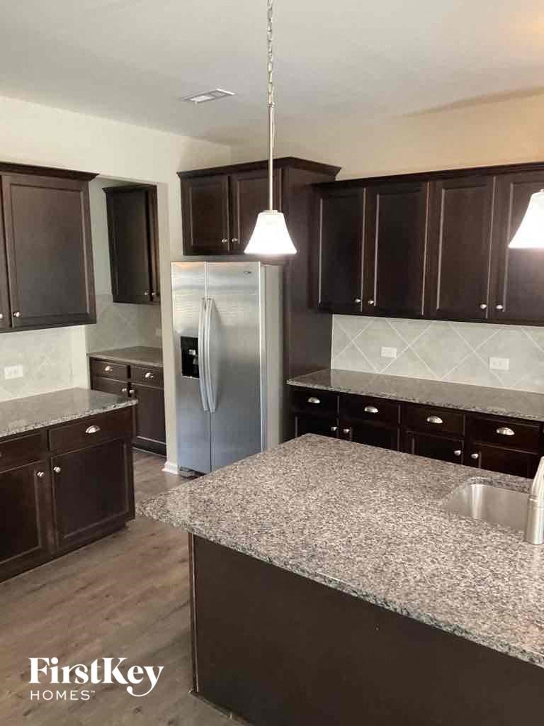 an image of a kitchen with granite counter tops and stainless steel refrigerator