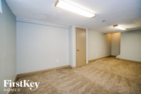 the living room and bedroom of an apartment with carpet and a door to a closet