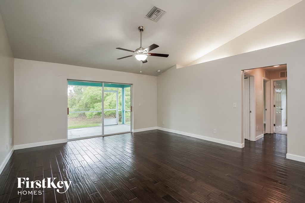 A spacious room with a ceiling fan and sliding glass doors leading to a garden.
