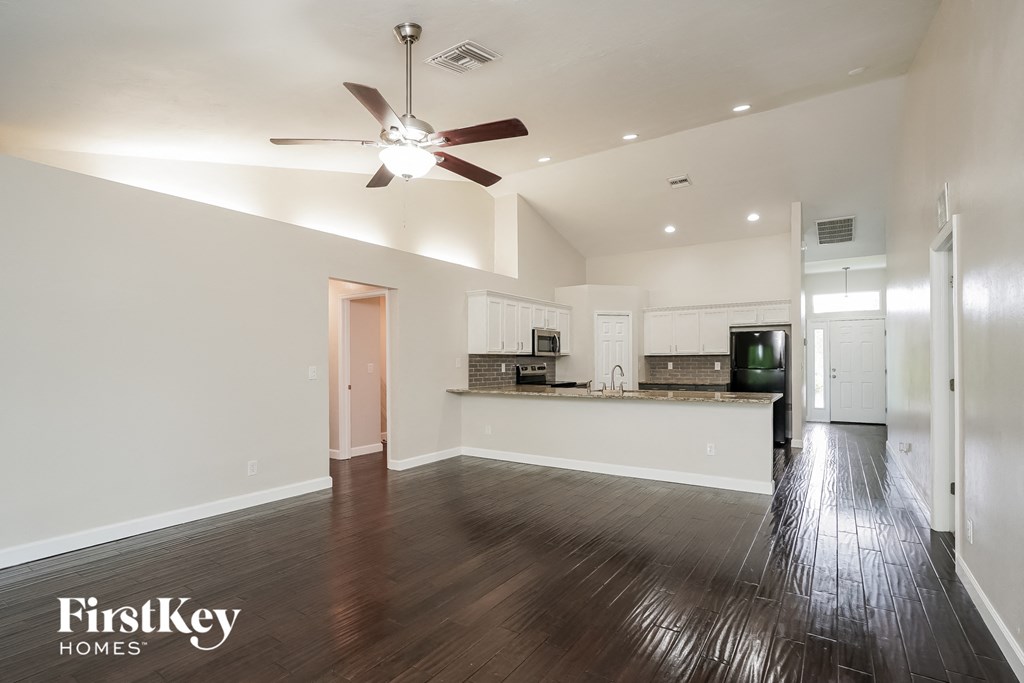 A spacious kitchen and living room with wood flooring and a ceiling fan.