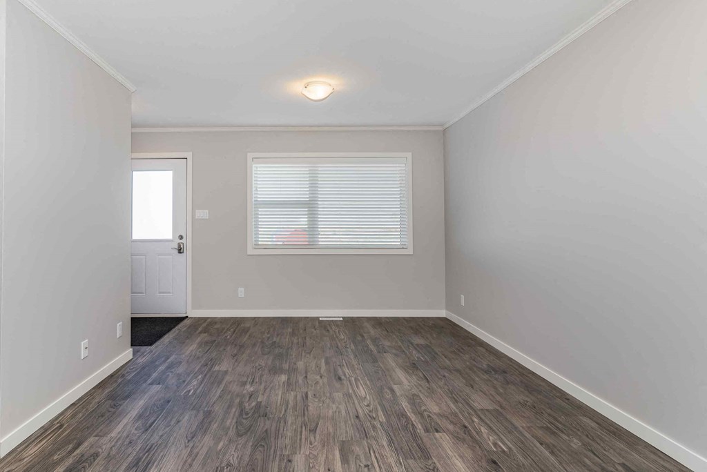 an empty living room with hardwood floors and a window