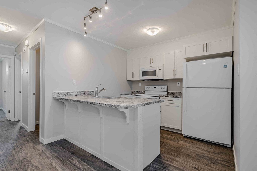a white kitchen with an island and a refrigerator