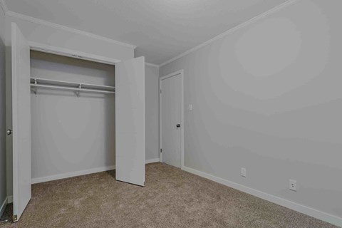 a bedroom with white walls and a closet with a door