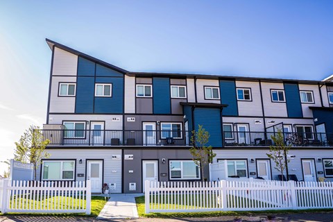 a row of colorful apartments with a white fence