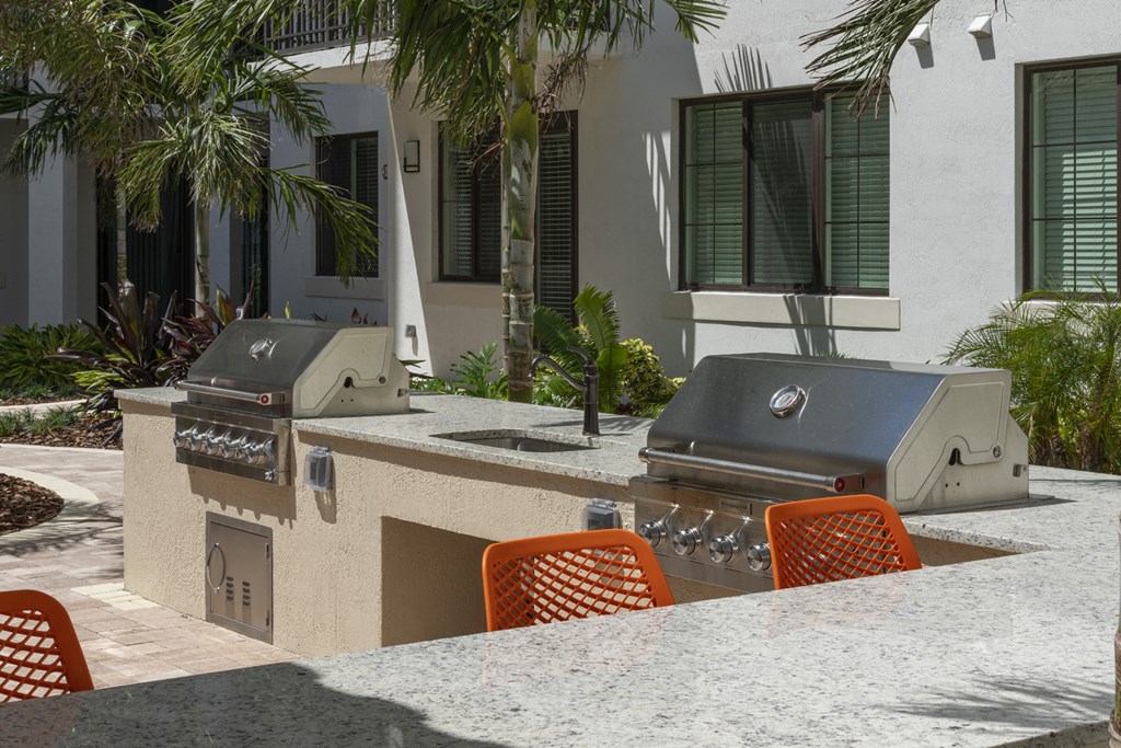 a patio with a grill and a table with chairs