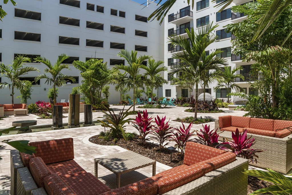 a courtyard with furniture and palm trees in front of a building