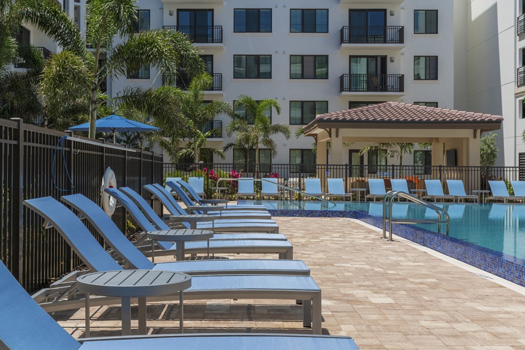 a pool with chairs and a building in the background