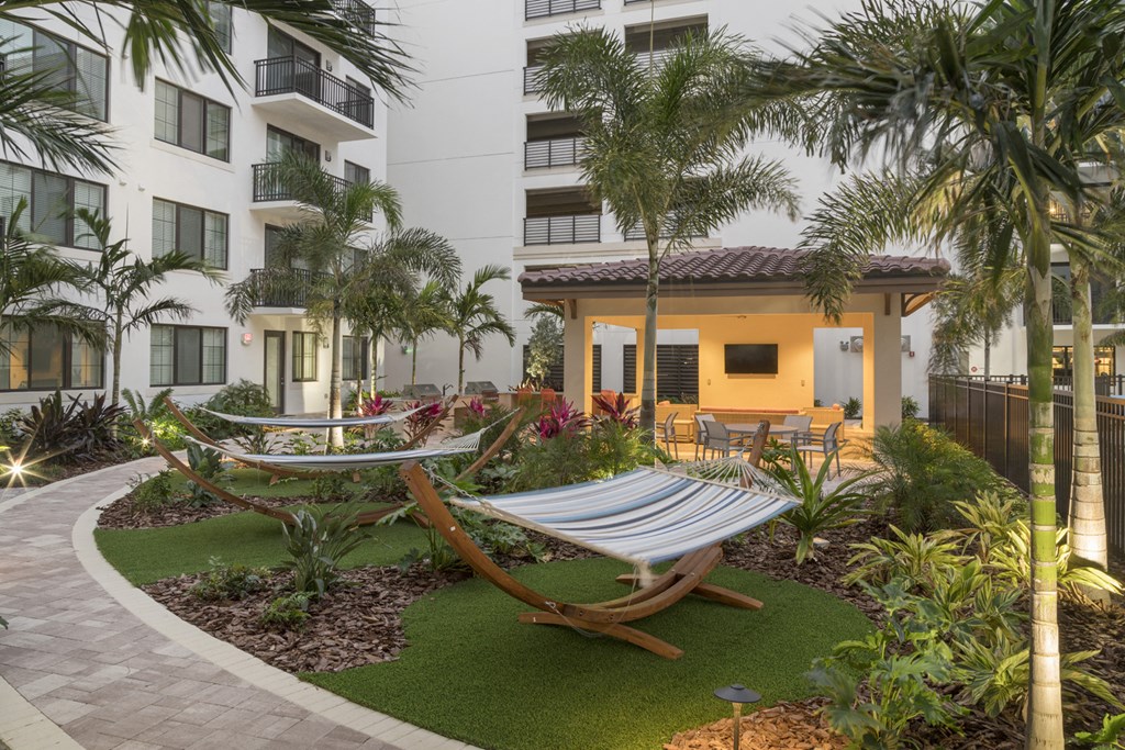 a courtyard with hammocks and palm trees in front of an apartment building