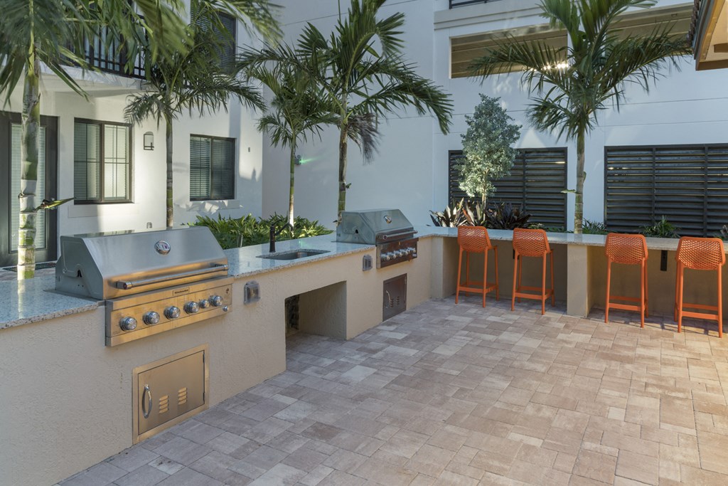 a kitchen with a bar and grill in a courtyard
