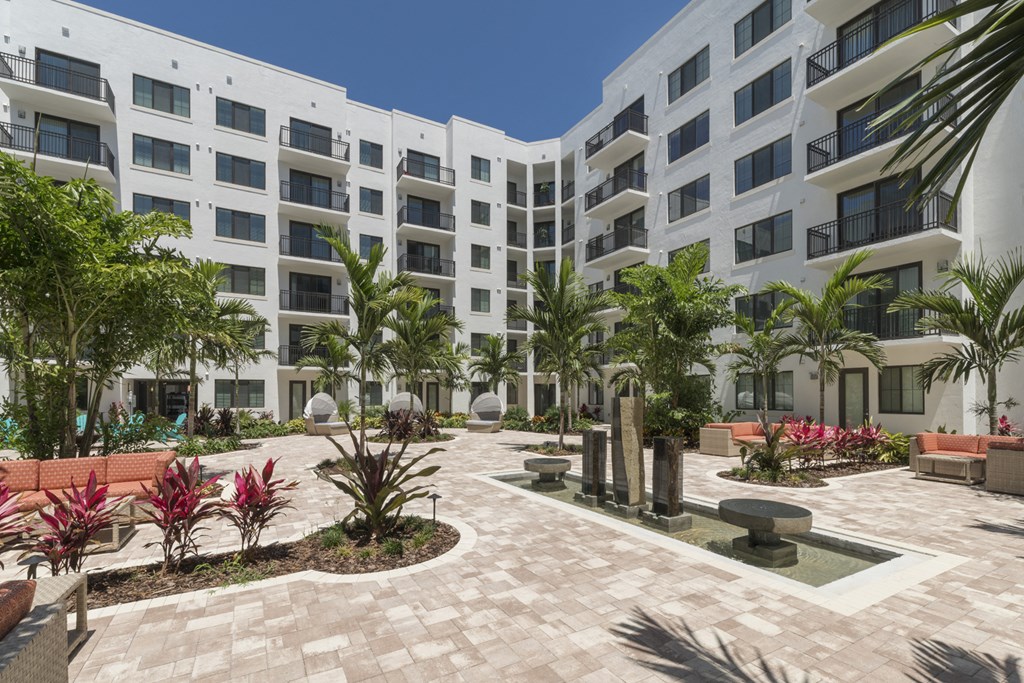 a building with a courtyard and palm trees in front of it