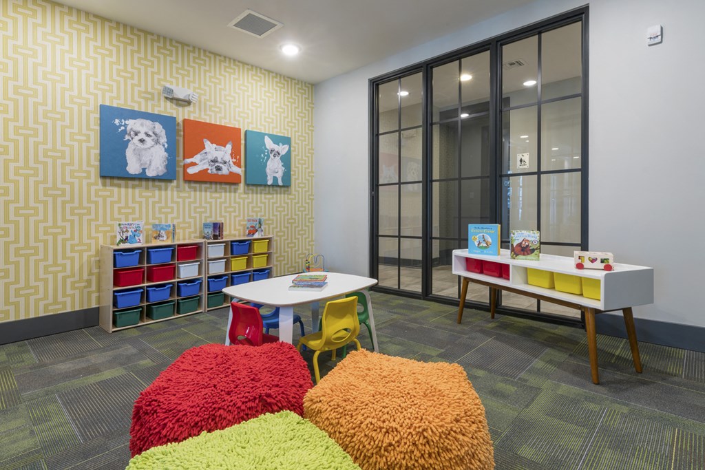 a play room with desks and chairs and artwork on the wall