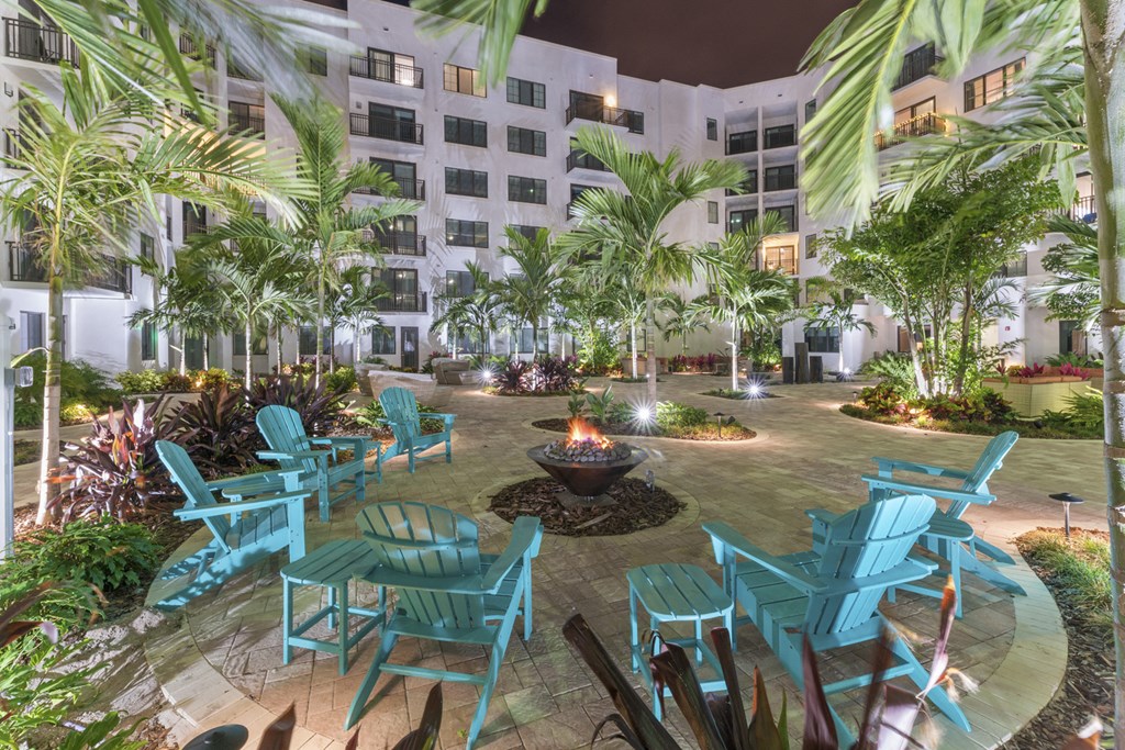 a courtyard with blue chairs and a fire pit