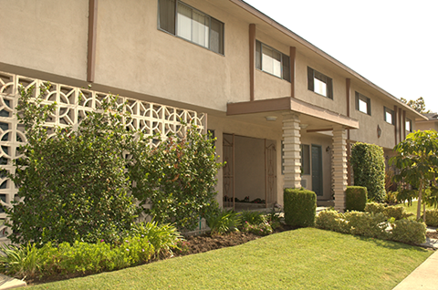 the front of a building with a manicured lawn and plants