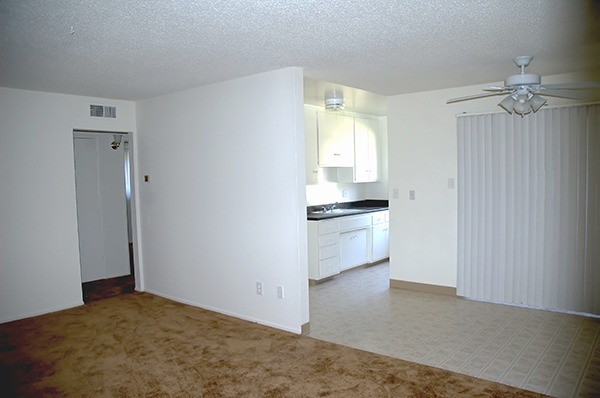 an empty living room and kitchen with a ceiling fan