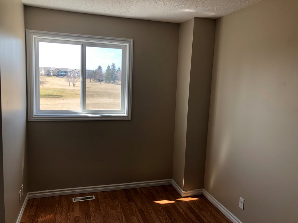 an empty room with a window and wooden floors