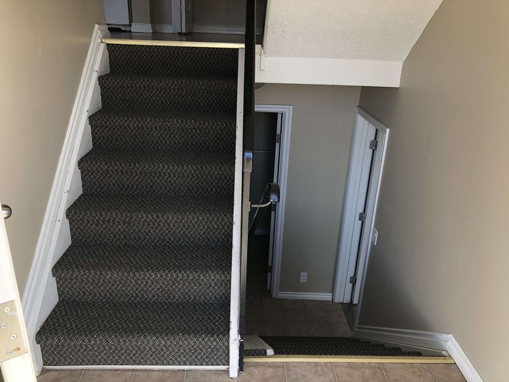 a staircase with carpeted stairs leading up to a door