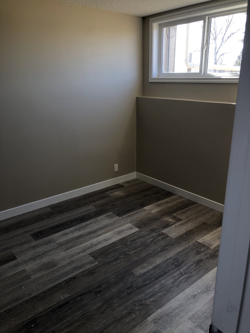 an empty room with wooden floors and a window