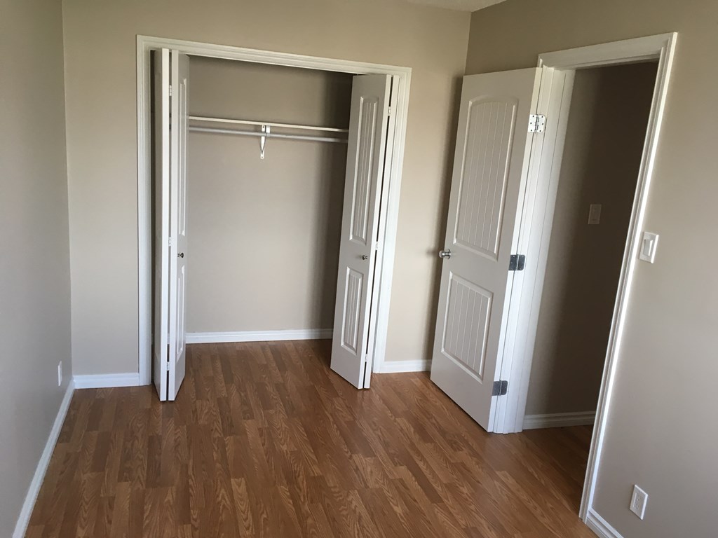 a bedroom with two closets and a hard wood floor