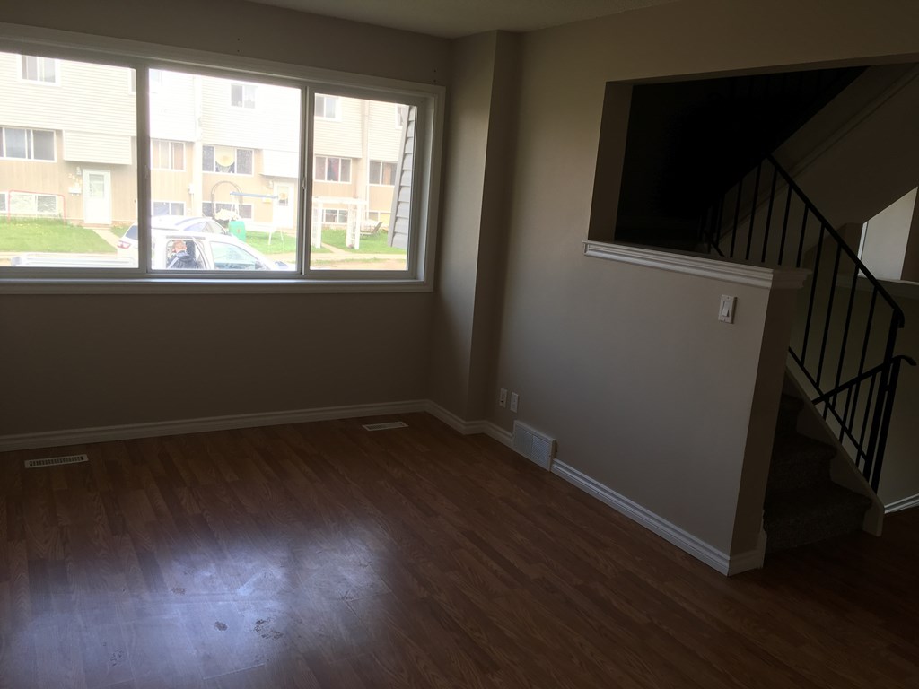 an empty living room with a large window and wooden floors