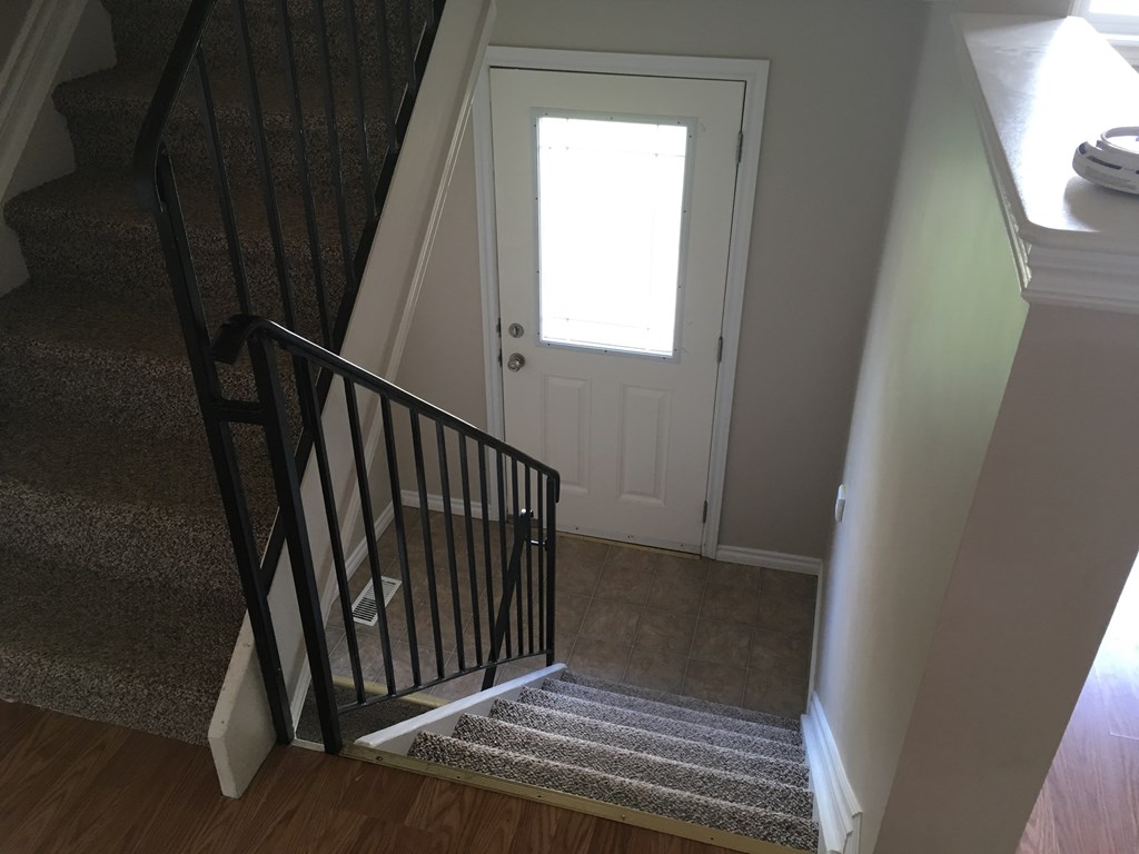 the view from the bottom of the stairs up to a white door with a window