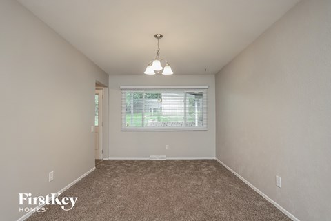 A room with a carpeted floor and a window with blinds.