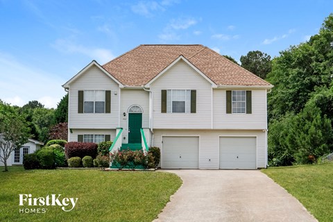 a white house with a driveway and a green door