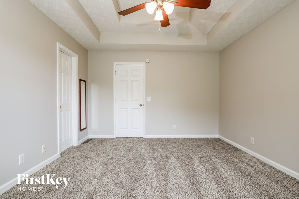the spacious living room with ceiling fan and carpet