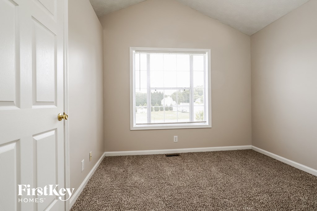 a bedroom with a window and a carpeted floor