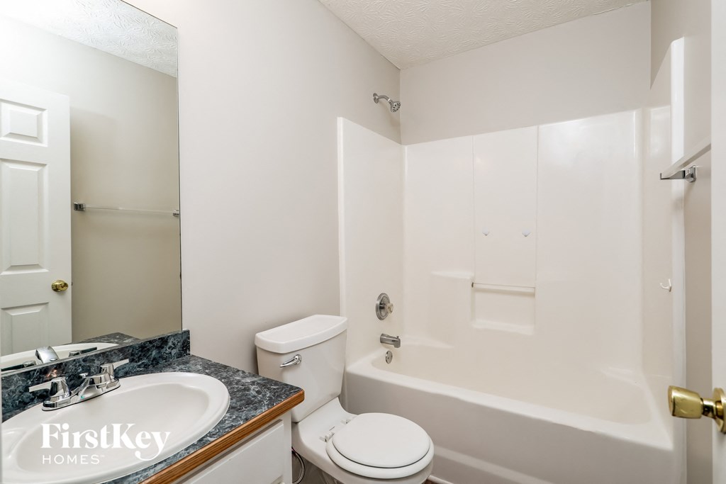 a white bathroom with a white toilet and a tub and a sink