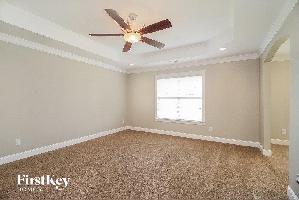the master bedroom has a carpeted floor and a ceiling fan