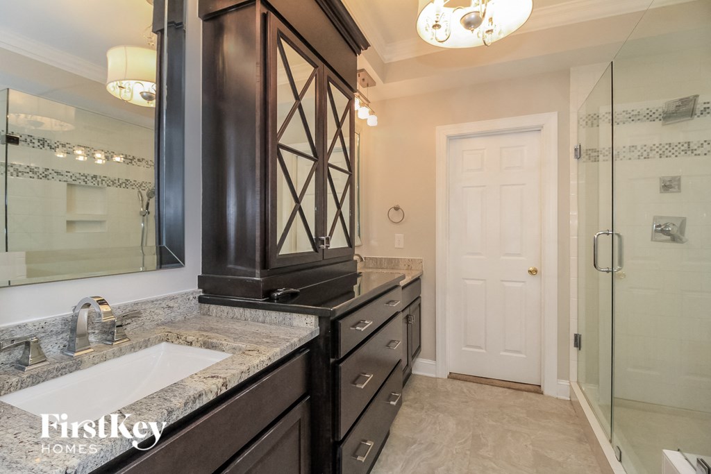 the master bathroom has a large vanity with a sink and a shower