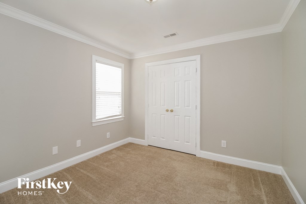 a room with a white door and a window and a carpet
