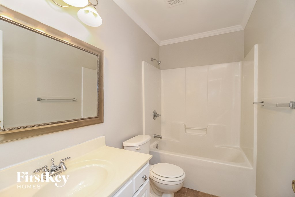 a white bathroom with a white toilet and a sink and a tub and a mirror