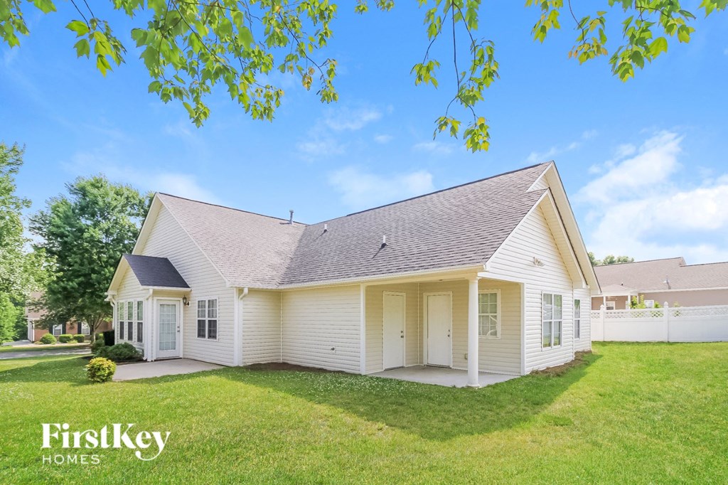 a white house with a grassy yard and a white fence