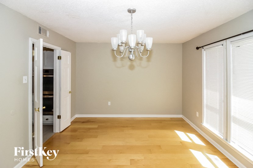an empty dining room with a chandelier and a door to the closet